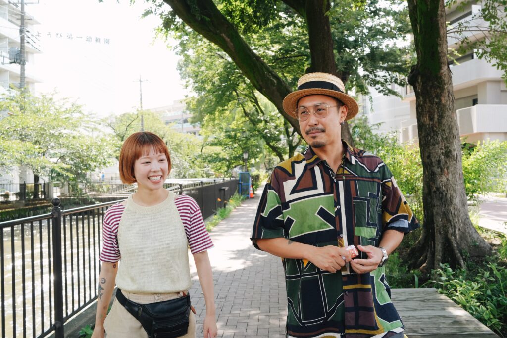 前橋の川沿いを笑顔で並んで歩く西澤康介さんと日菜子さん